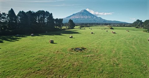 AERIAL: flying over farm and hay bails looking out to Mt Taranaki / Mt Egmont, New Zealand