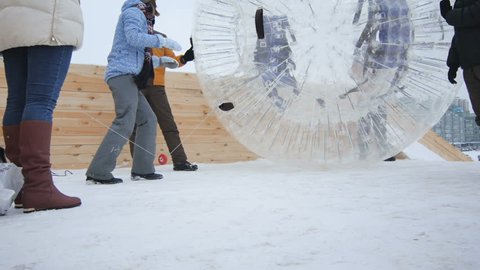 KAZAN, TATARSTAN/RUSSIA - DECEMBER 13 2016: Brave blonde girl jumps into extreme zorb and invites inside to have fun in winter park in cold weather on December 13 in KAZAN