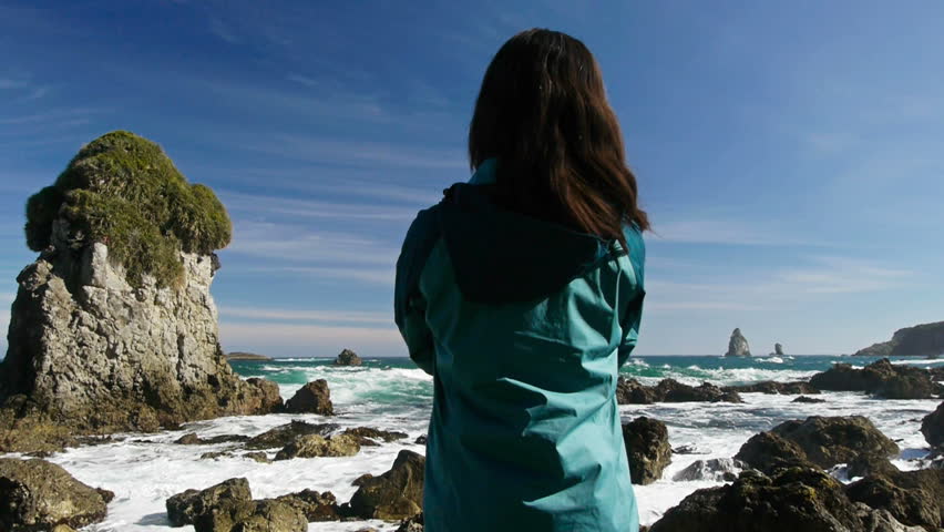 Woman looks out over rough ocean