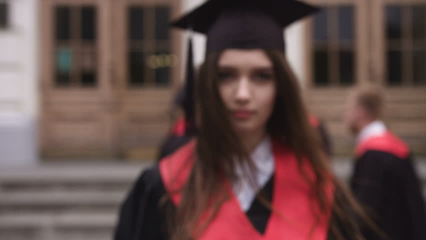 Portrait of a beautiful young woman graduate is looking at the camera and smiling in the background graduates | Shutterstock HD Video #29721394