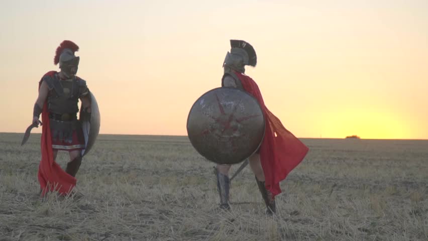 Two gladiators learn to fight and defend themselves in the middle of the field, shooting before dawn. Slow motion