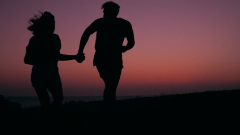 Silhouette of Young Teenage Couple in Love Running and Spinning at Beautiful Pink Sunset. HD Slowmotion Carefree Lifestyle Footage. Stock Video