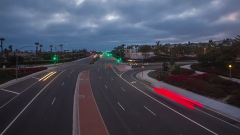 Timelapse in motion or hyperlapse at twilight in Newport Beach over Pacific Coast Highway (PCH) day into night with traffic below and clouds racing overhead.