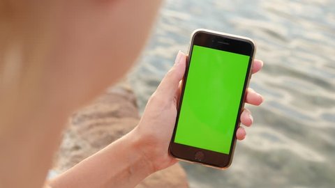 NICE, FRANCE - JULY 2017: Woman holds green screen smart phone at the beach