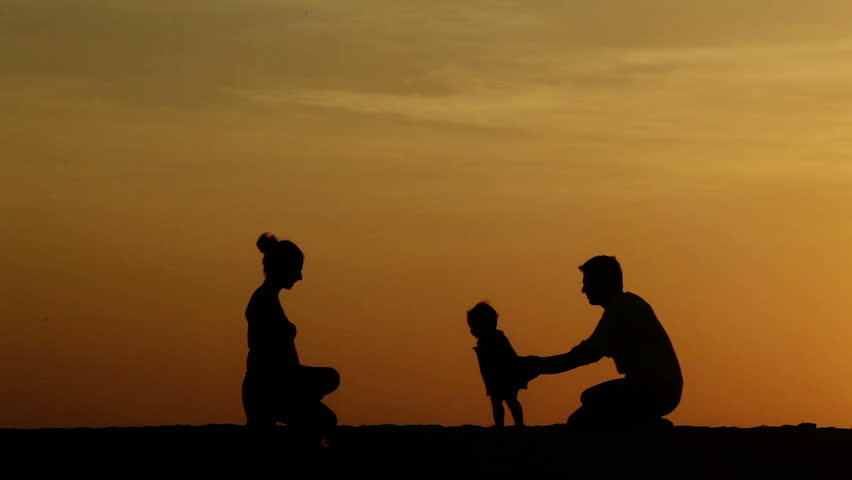 Silhouette of parents teaching their daughter walking
