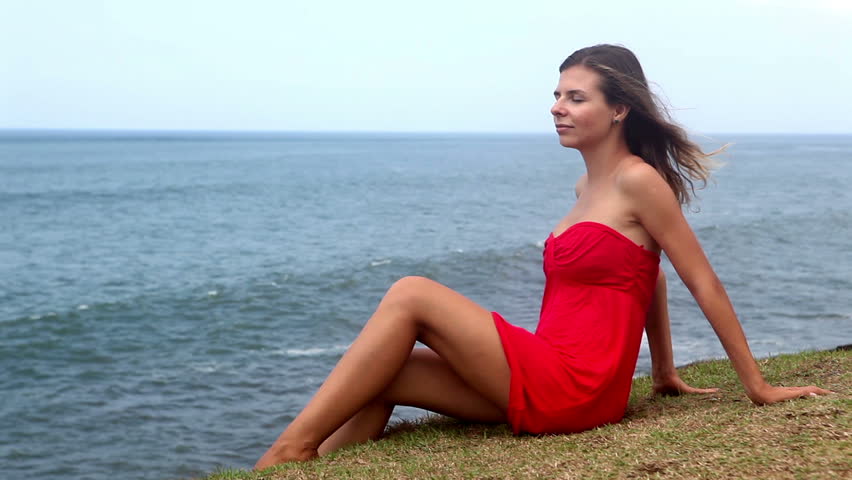 Pretty young woman in red dress enjoying at the beach