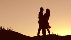 Couple in love dancing silhouette at sunset and nature kissing. Loving man and woman with dog dancing silhouette slow motion video