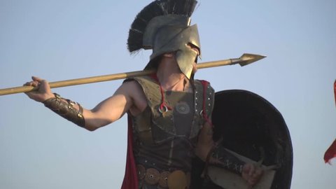 An aggressive Roman warrior beats a spear from behind his shoulder, slow motion