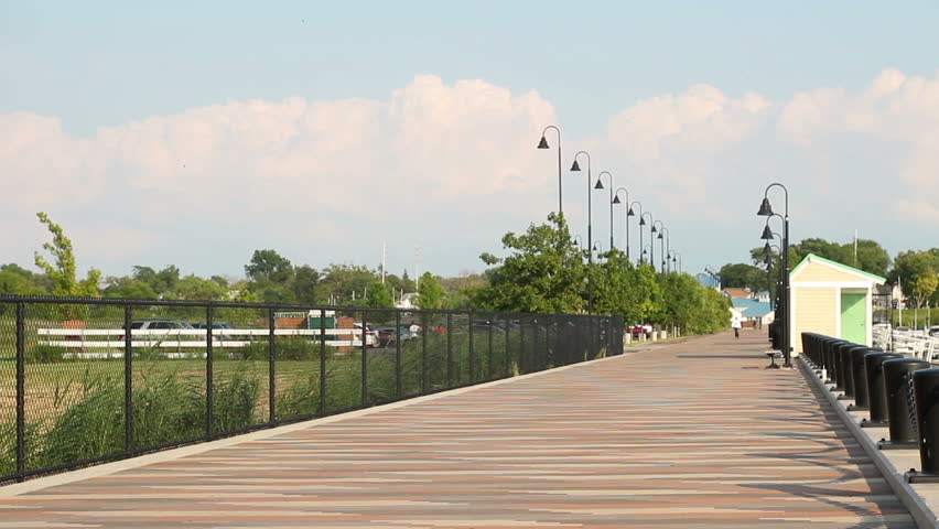 Man walks down the pier or docking bay of marina in summertime