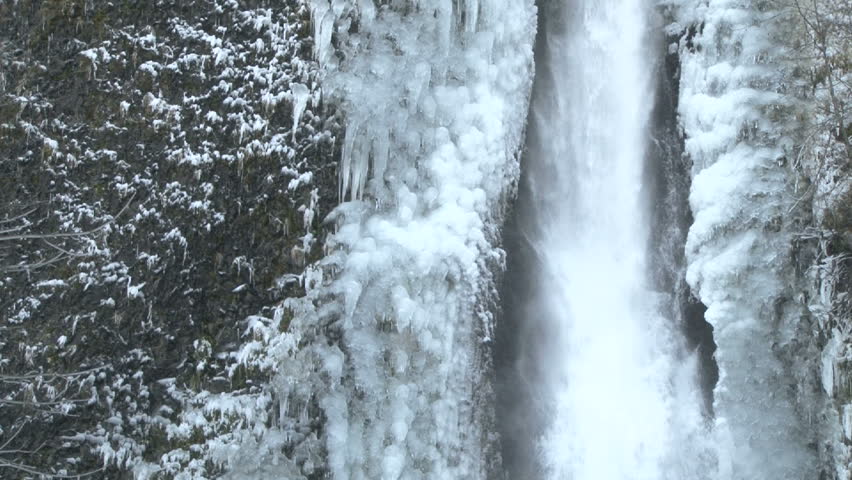 Icicles formed on flowing waterfall after winter storm.