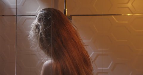 The close-up side portrait of the attractive blonde woman taking the shower.
