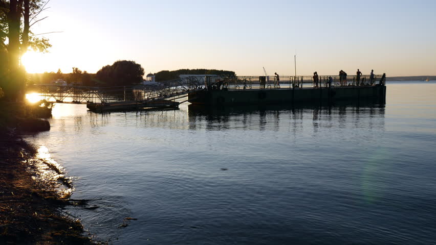People rest and fish from the pier on the sea.