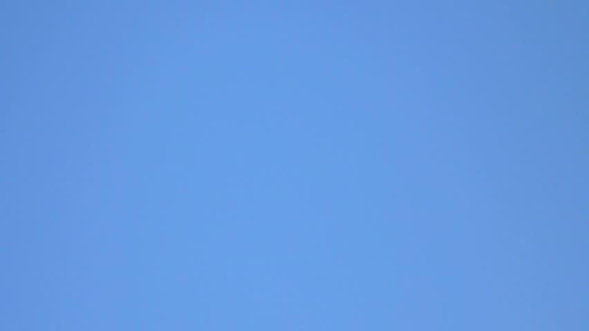 Simple blue sky with commercial passenger airplane flying overhead.
