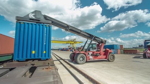 timelapse gantry crane and reachstacker unload freight containers from platforms on container yard