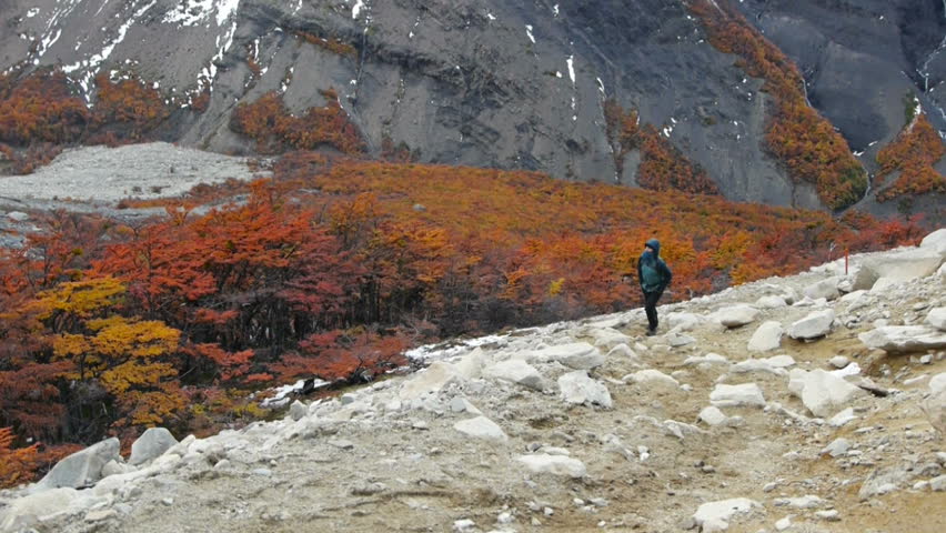 Woman walks up path in Torres del Paine national park during autumn