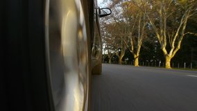 Driving a black sports / super car on a country road. Wheel spinning POV - Point of View, day country side, sunset, fall . Trees on the side. Fast Speed / time-lapse. Right side wheel / driving UK 