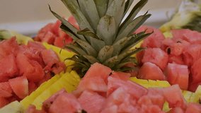 Watermelon and pineapple are cut into pieces on a tray.