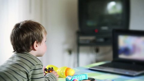 Little boy watching cartoons at laptop and eating apples