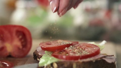 Hand sprinkle spices on tasty sandwich, slow motion shot at 240fps
