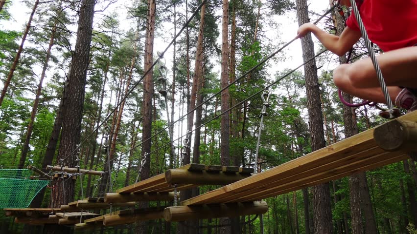 Small girl in adventure park. Adventure park is place which can contain wide variety of elements, such as rope climbing exercises, obstacle courses and zip-lines. They intended for recreation.