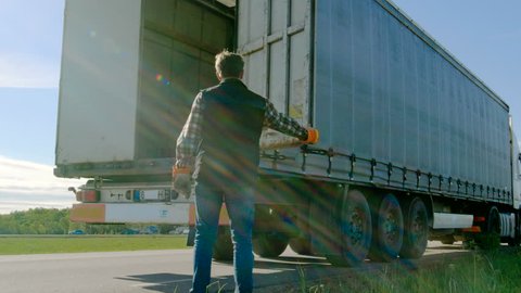 Truck Driver Closes Doors of His Parked Truck Cargo Trailer. Professional Driver Wears Heavy Duty Gloves. Shot on RED EPIC-W 8K Helium Cinema Camera.