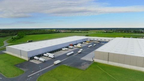 Aerial Shot of Industrial Warehouse/ Storage Building/ Loading Area where Many Trucks Are Loading/ Unloading Merchandise. Shot on Phantom 4K UHD Camera.