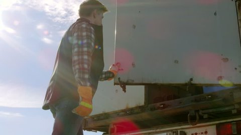 Truck Driver Closes Doors of His Truck Cargo Trailer. Professional Driver Wears Heavy Duty Gloves. Shot on RED EPIC-W 8K Helium Cinema Camera.
