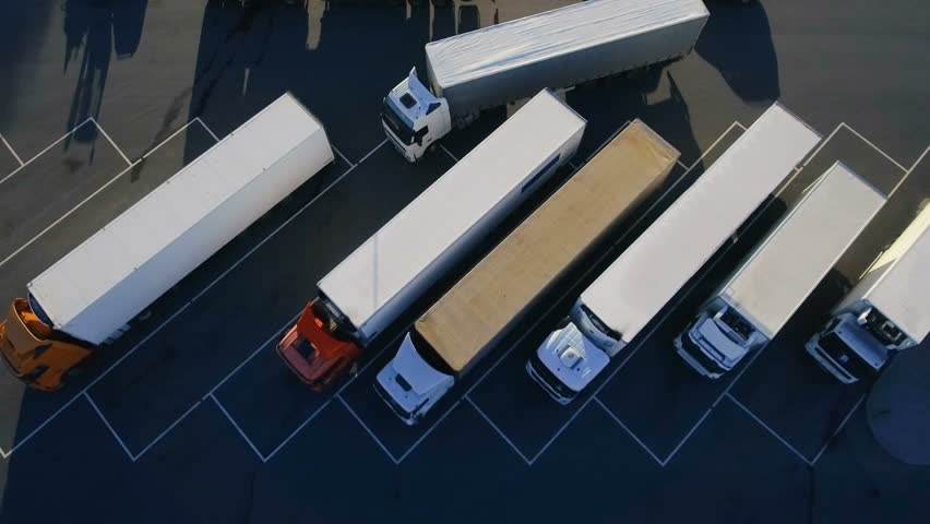 Aerial Top View of White Semi Truck with Cargo Trailer Parking with Other Trucks on Special Parking Lot. Shot on Phantom 4K UHD Camera. Royalty-Free Stock Footage #29799949