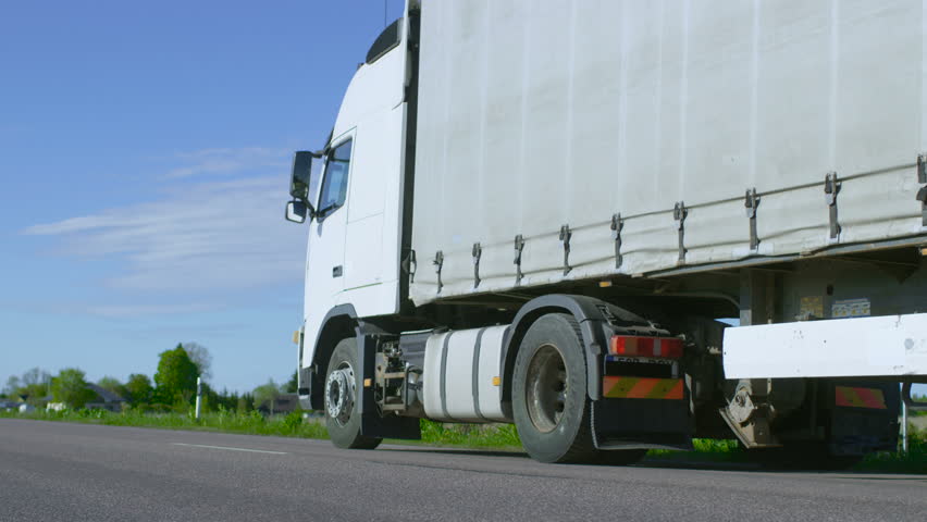 Truck Driver Crosses the Road in the Rural Area and Gets into His White Semi Truck with Cargo Trailer Attached. Sun Shines and Highway is Empty. Shot on RED EPIC-W 8K Helium Cinema Camera. Royalty-Free Stock Footage #29800003