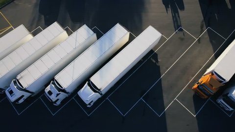 Moving Aerial Top View of Parked Semi Trucks with Cargo/ Refrigerator Trailers Standing on their Dedicated Parking Places. Shot on Phantom 4K UHD Camera.