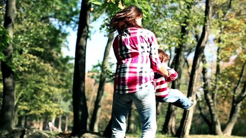Young mother having fun with her son in beautiful autumn park, slow motion
