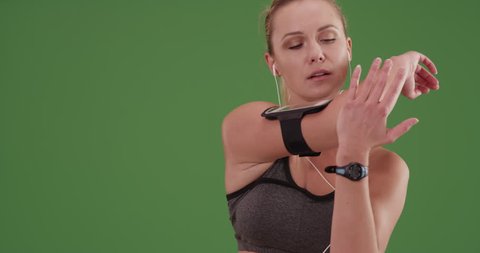 Woman runner stretching on green screen. On green screen to be keyed or composited.