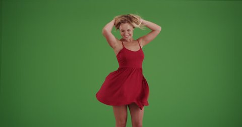 Carefree woman dancing in red dress on green screen. On green screen to be keyed or composited.