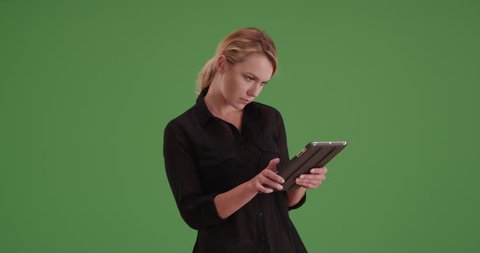 Businesswoman using tablet on green screen. On green screen to be keyed or composited.
