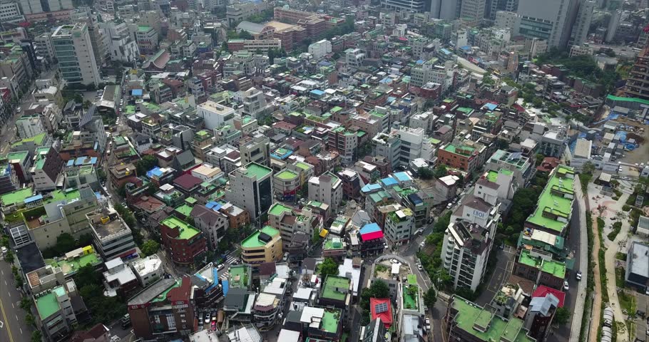 Aerial view above Hongdae shopping streets, dense rooftops, pedestrians, traffic, and surrounding Seoul neighborhoods, 2017.
