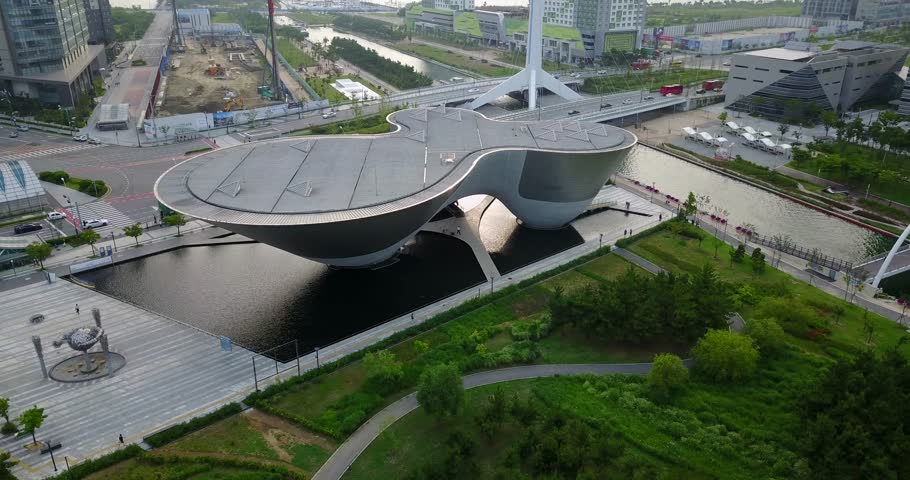 Aerial view over sculptural Incheon Central Park buildings, landscaped waterways, broad roads, and Songdo towers, 2017.