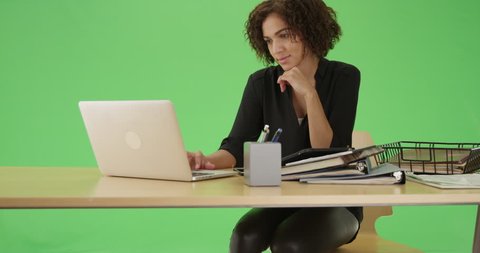 Millennial African American woman on her laptop at her desk on green screen. On green screen to be keyed or composited.
