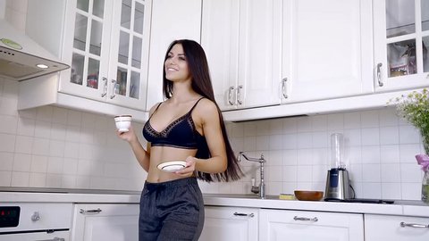 Happy young woman dancing in the kitchen in my pajamas in the morning to listen to music and coffee house