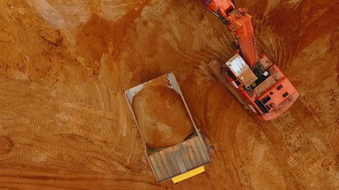 Top view of excavator pouring sand in dump truck.View from above of mining machinery. Mining industry. Mining equipment working at sand mine