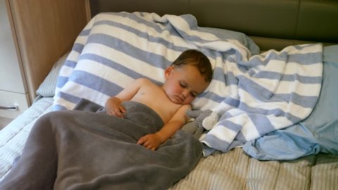 A cute little toddler lies in his bed while sick with the flu
