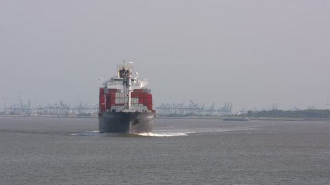 BATH, NETHERLANDS - JUNE 2017: Container ship Cap Beatrice navigates on the Western Scheldt, in a notorious section called The Bocht van Bath (the curve of Bath). Skyline Antwerp port in background.