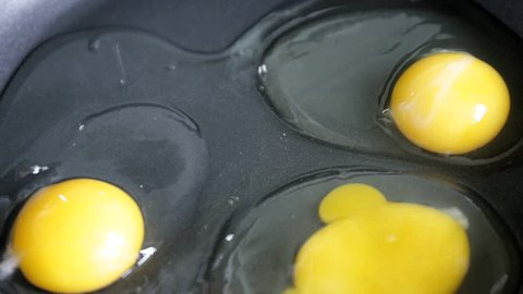 Putting fried eggs from a hen's egg on a greased black frying pan with yellow yolk