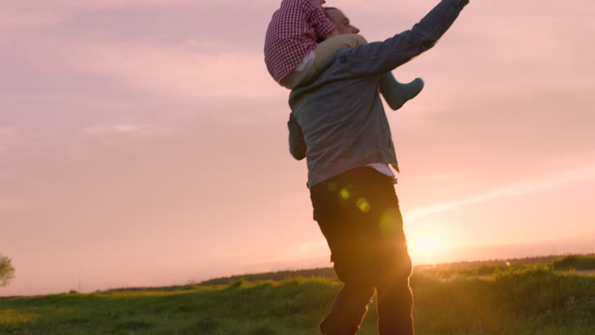 Happy family is playing flying kite at sunset. Son is sitting on his father's neck Royalty-Free Stock Footage #29837686