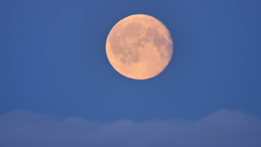 Bright full moon rising over clouds close up
