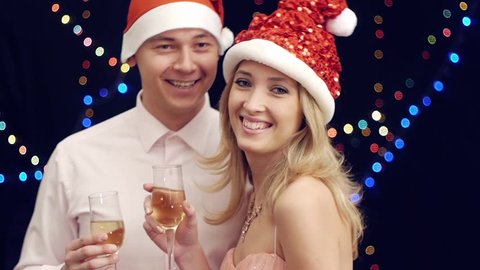 Happy man in santa claus hat bring drink to woman at christmas party
