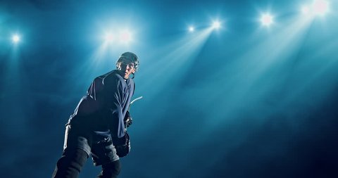 Ice Hockey player hits a puck on a dark background with intensional lens flares. He is wearing unbranded sports clothes.