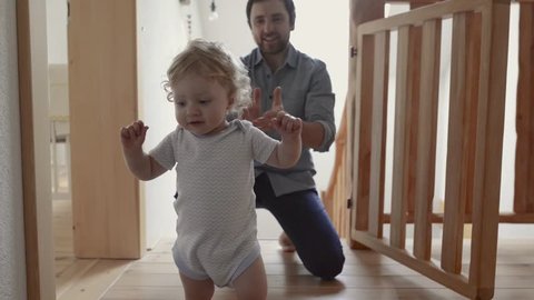 Young father at home with his little son doing first steps.