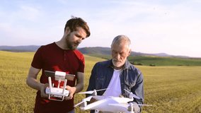 Senior father and his son with drone outdoors.