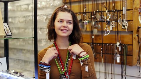 Female offering to buy necklace and bracelets in the shop of jewelry
