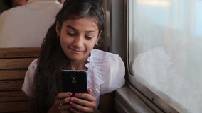 A little gypsy girl using a smartphone on the train